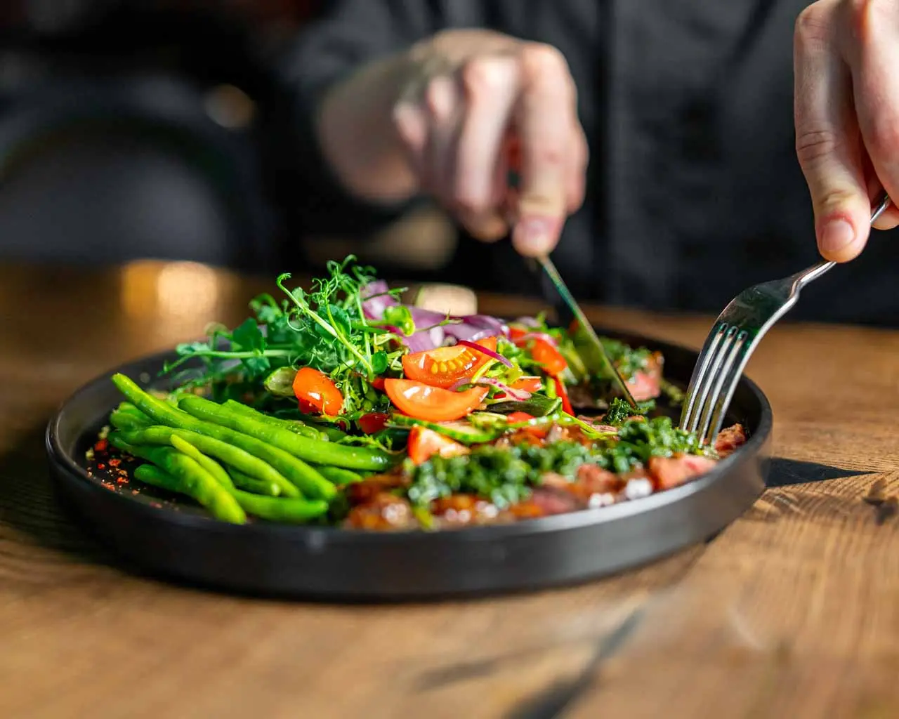a close up of a persons hands getting ready to eat salad